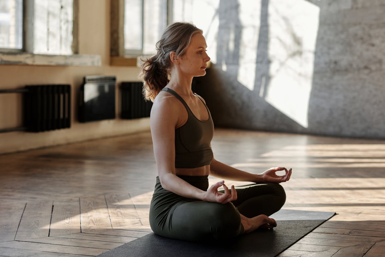 A woman meditates in a peaceful yoga pose indoors, embracing wellness and relaxation.